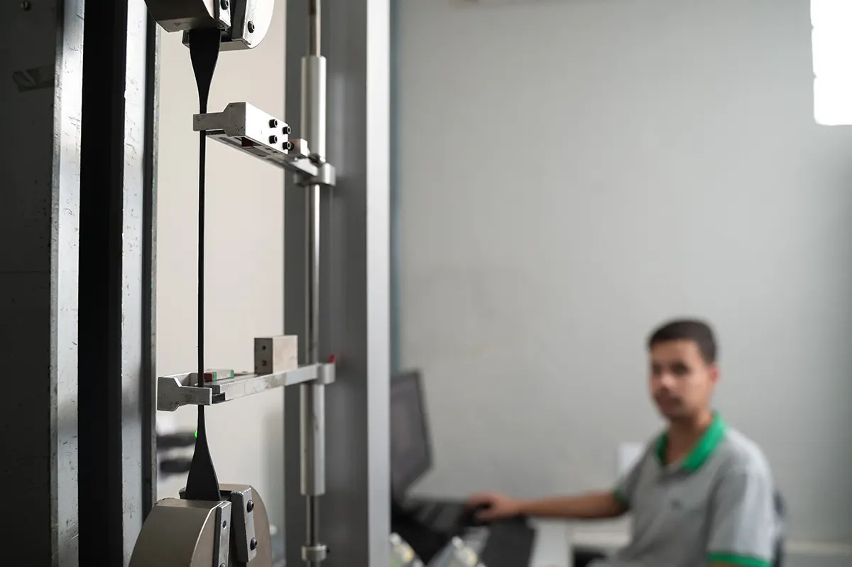 Corpo de prova de plástico preso nas garras da máquina universal da Labmor